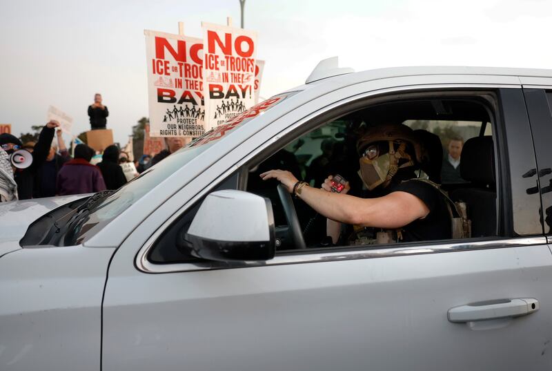 A U.S. Customs and Border Patrol agent tries to drive through a crowd of protesters outside Coast Guard Island