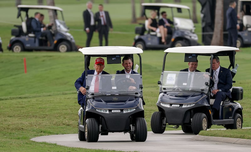 President Donald Trump and his son, Eric Trump, drive in a golf cart after he arrived on Marine One at the LIV Golf tournament being held at his Trump National Doral Golf Club on April 03, 2025 in Doral, Florida.