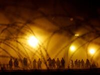 Migrants stand near the border wall