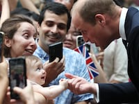 8 month old Albane Costa holds the finger of Prince William, Prince of Wales during his visit to the HSBC Rain Vortex at Jewel Changi Airport on day one of his visit to Singapore