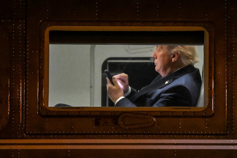 TOPSHOT - US President Donald Trump uses a cellphone aboard Marine One before it departs Leesburg Executive Airport in Leesburg, Virginia, on April 24, 2025. Trump is returning to the White House after attending a MAGA, Inc. dinner at the Trump National Golf Club Washington, DC. (Photo by Alex WROBLEWSKI / AFP) (Photo by ALEX WROBLEWSKI/AFP via Getty Images)