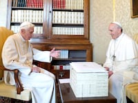 Pope Francis and Pope Benedict XVI meet in 2013 and Castel Gandolfo, with a big white box sitting between them.