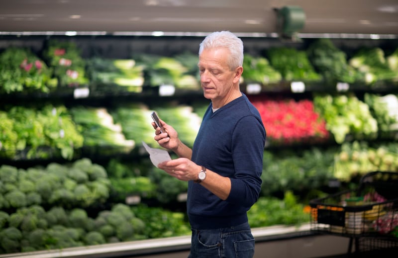 Mature man checks his list while shopping for vegetables.