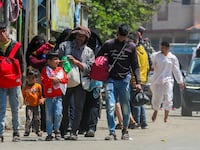 Gazans evacuate Rafah, carrying their belongings with their heads hung.