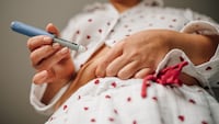 Close-up of woman administering insulin shot to stomach using injection pen.
