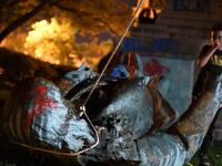 A young boy stands near the statue of Confederate general Albert Pike after it was toppled by protesters at Judiciary Square in Washington, DC on late June 19, 2020. -