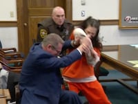 A screenshot of video showing Taylor Schabusiness attacking her lawyer in a court room