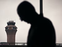 A man stands in front of an airport control tower at Newark, New Jersey.