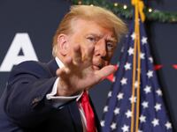 Former President Donald Trump waves at a campaign event before a flag.