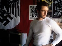 Edward Norton poses in front of a Nazi flag.