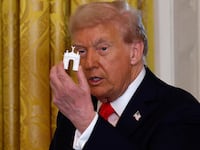 President Donald Trump holds models of an arch as he delivers remarks during a ballroom fundraising dinner in the East Room of the White House on October 15, 2025 in Washington, DC.