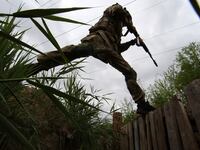 An armed National Guard serviceman jumps across a trench outside Kharkiv in Ukraine.