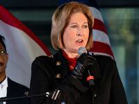 Sidney Powell holds a microphone while she speaks at a press conference in Georgia.