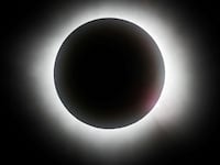 The sun slips behind the moon in a total solar eclipse.
