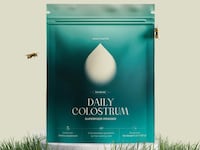 A green bag of Healthletic powder on a neutral background. The bag is in a patch of grass with two bees flying around it.