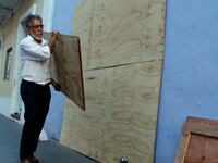 A man boards up windows of a business in preparation for Hurricane Maria in San Juan, Puerto Rico