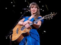 Taylor Swift holding a guitar during the Eras Tour “Surprise Songs” section.