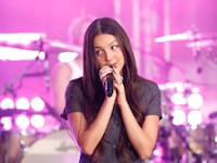 Olivia Rodrigo with a microphone near her face as she performs