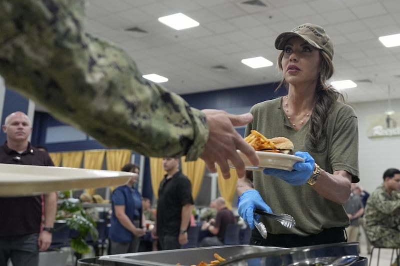 Kristi Noem helps served food to sailors and coast guardsmen in Bahrain.