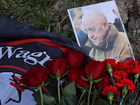 A photo of Yevgeny Prigozhin with the Wagner Group flag and red flowers.