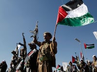 Yemenis recently militarily trained by the Houthi movement holding up their guns and Palestinian flag chant slogans