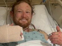 A smiling Matthew Reum gives a thumbs up from his hospital bed.