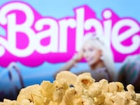 A popcorn and Barbie movie website displayed on a screen in the background
