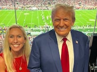 Marjorie Taylor Greene and Donald Trump pose together at an Alabama football game.