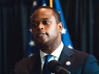 A photo of Daniel Cameron grimacing in front of a microphone