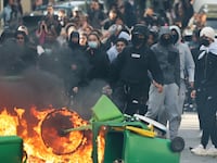 TOPSHOT - A student puts trashes into a fire as protesting students carry out blockading action near place de la Nation, in Paris, on October 2, 2026. Since late September, students have staged protests outside schools over grievances ranging from timetables, class sizes and a shortage of teachers to overheated classrooms during this year's heatwaves. The protests started in the Ile-de-France region around Paris but have now spread to other cities nationwide. (Photo by Thomas SAMSON / AFP via Getty Images