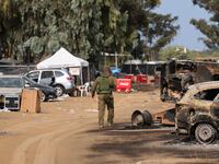 An Israeli soldier walks past burned vehicles at the site of the weekend attack on the Supernova desert music festival by Palestinian militants near Kibbutz Reim.
