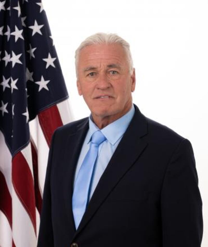 Dr. George Tidmarsh stands in front of an American flag.