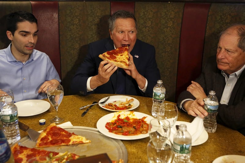 A photo of Eric Ulrich with then-presidential candidate John Kasich (R-OH), eating pizza.