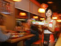 A Hooters waitress carries a tray past a table of customers in Beijing.