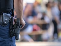 A police officer monitors a parade, with his gun in frame.