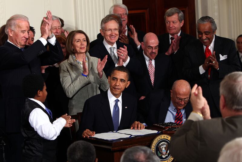 Speaker Pelosi stands behind President Barack Obama after he signed the Affordable Health Care for America Act during a ceremony with fellow Democrats in the East Room of the White House March 23, 2010 in Washington, DC.