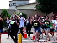 Shoppers leave with their hands up after police responded to a gunman who shot and killed eight people and wounded at least seven others at Allen Premium Outlets mall north of Dallas.
