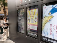 Women look at a display showing a digital poster for Hayao Miyazaki's latest film, “How Do You Live?”
