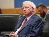 John Eastman sits with his hands crossed in a courtroom.