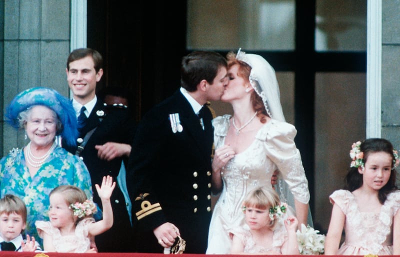 Prince Andrew is seen kissing Sarah Ferguson on the balcony, after their wedding ceremony at Buckingham Palace in this photo. Queen Elizabeth the Queen Mother and Prince Edward stand to the right of the couple.