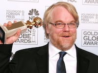 Philip Seymour Hoffman posing on the red carpet with his Golden Globe award.