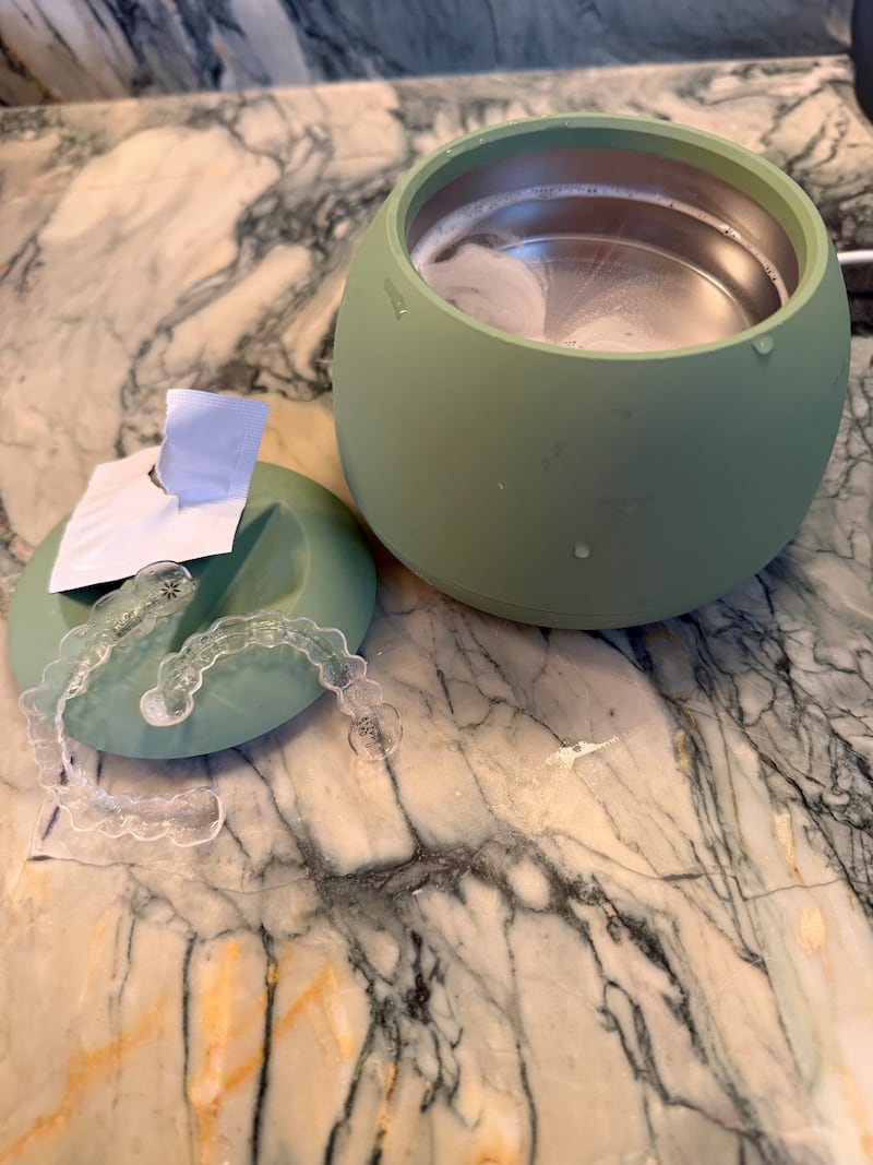 Colleen's Invisalign aligners in their cleaning pod.