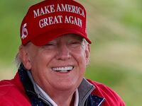 Donald Trump smiles while golfing.