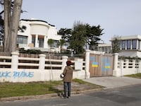 A person looks at anti-Putin graffiti and painted Ukrainian flags at a villa believed to belong to Lyudmila Ocheretnaya, former wife of Russian president Vladimir Putin, in Anglet, France, March 1, 2022.