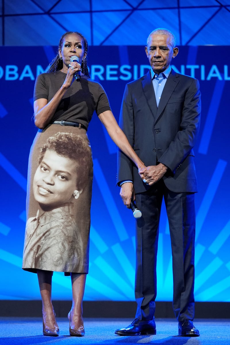 Former U.S. President Barack Obama holds the hand of former U.S. first lady Michelle Obama, who is wearing a skirt featuring a vintage photograph of her mother, Marian Robinson, as they deliver remarks at a stakeholders’ event at the Obama Presidential Center in Chicago, Illinois, in 2026.