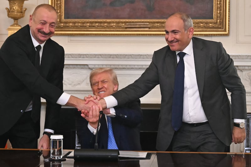 Donald Trump (C), Azerbaijani President Ilham Aliyev (L) and Armenian Prime Minister Nikol Pashinyan shake hands after signing an agreement in the State Dining Room of the White House in Washington, DC, on August 8, 2025.