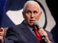 Mike Pence points his right hand as he holds a microphone.