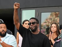 Diddy raising his fist with DJ Khaled behind him