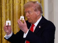 WASHINGTON, DC - OCTOBER 15: U.S. President Donald Trump holds models of an arch as he delivers remarks during a ballroom fundraising dinner in the East Room of the White House on October 15, 2025 in Washington, DC. Trump hosted organizations and individuals for a fundraising dinner for the new $250 million ballroom addition currently under construction at the White House. (Photo by Kevin Dietsch/Getty Images)