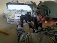 An Israeli soldier aims a weapon as they operate in the Gaza Strip, after a temporary truce between Israel and the Palestinian Islamist group Hamas expired, in this handout picture released on Dec. 1, 2023.